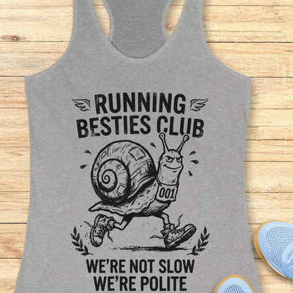 Gray tank top with a snail graphic and text 'Running Besties Club' on a wooden surface.