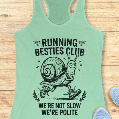 Light green tank top with a snail graphic and text  'Running Besties Club'  on a wooden surface