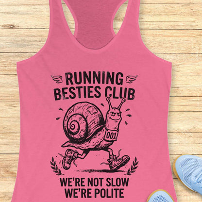 Pink tank top with a snail graphic and text  'Running Besties Club'  on a wooden surface