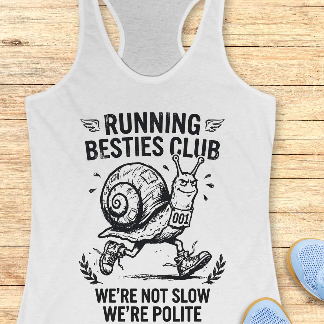 white tank top with a snail graphic and text 'Running Besties Club' on a wooden surface.