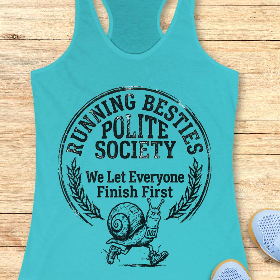 Turquoise tank top with 'Running Besties Polite Society' text and snail graphic on a wooden surface.