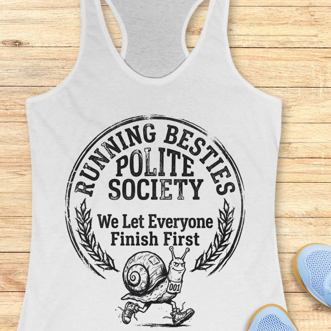 white tank top with 'Running Besties Polite Society' graphic on a wooden surface