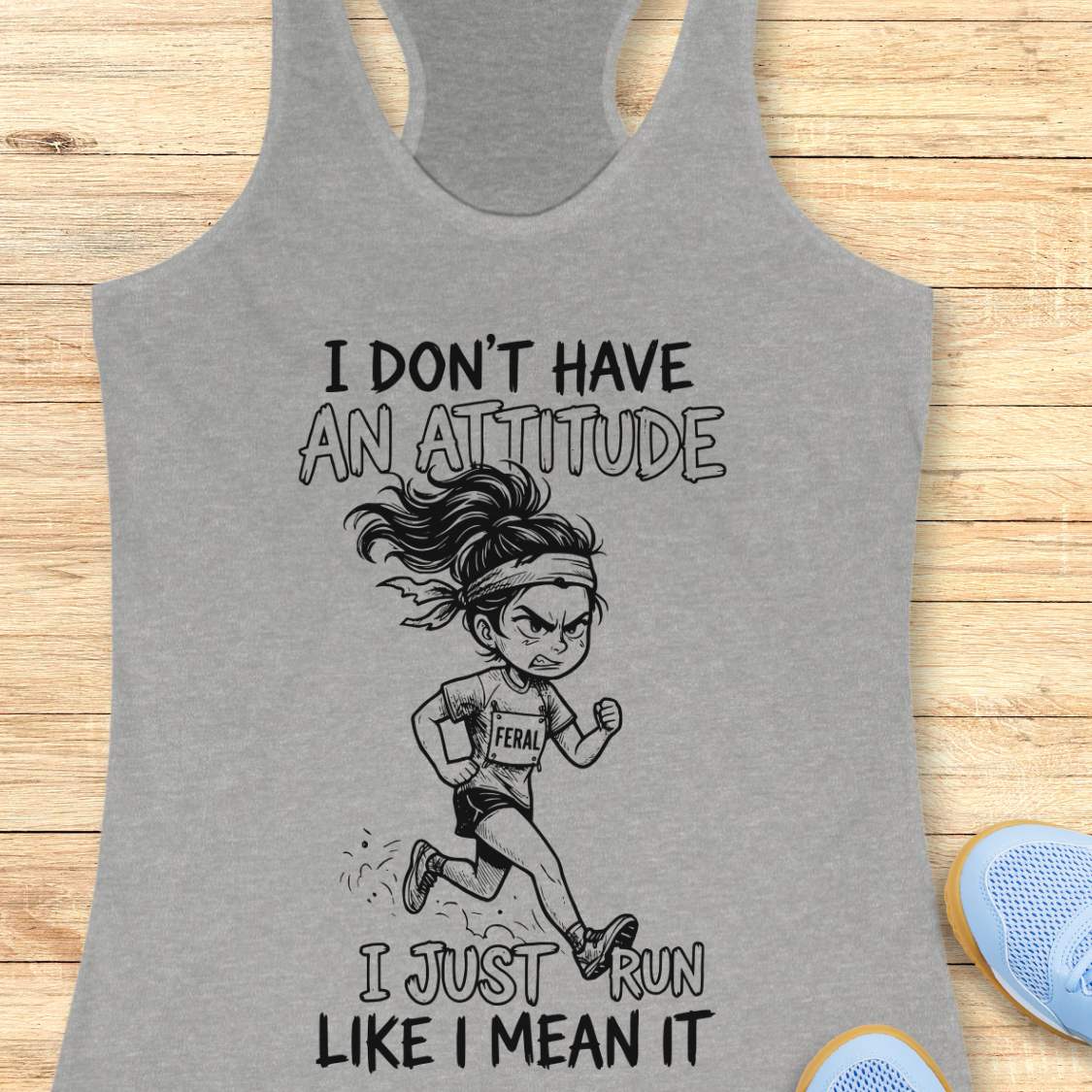Gray tank top with a graphic of a running person and text I don't have an attitude, I just run like I mean it, on a wooden surface