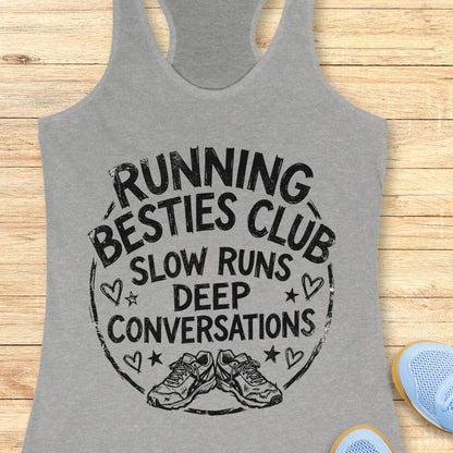 grey tank top with a graphic and text Running besties club, slow runs, deep conversations, on a wooden surface