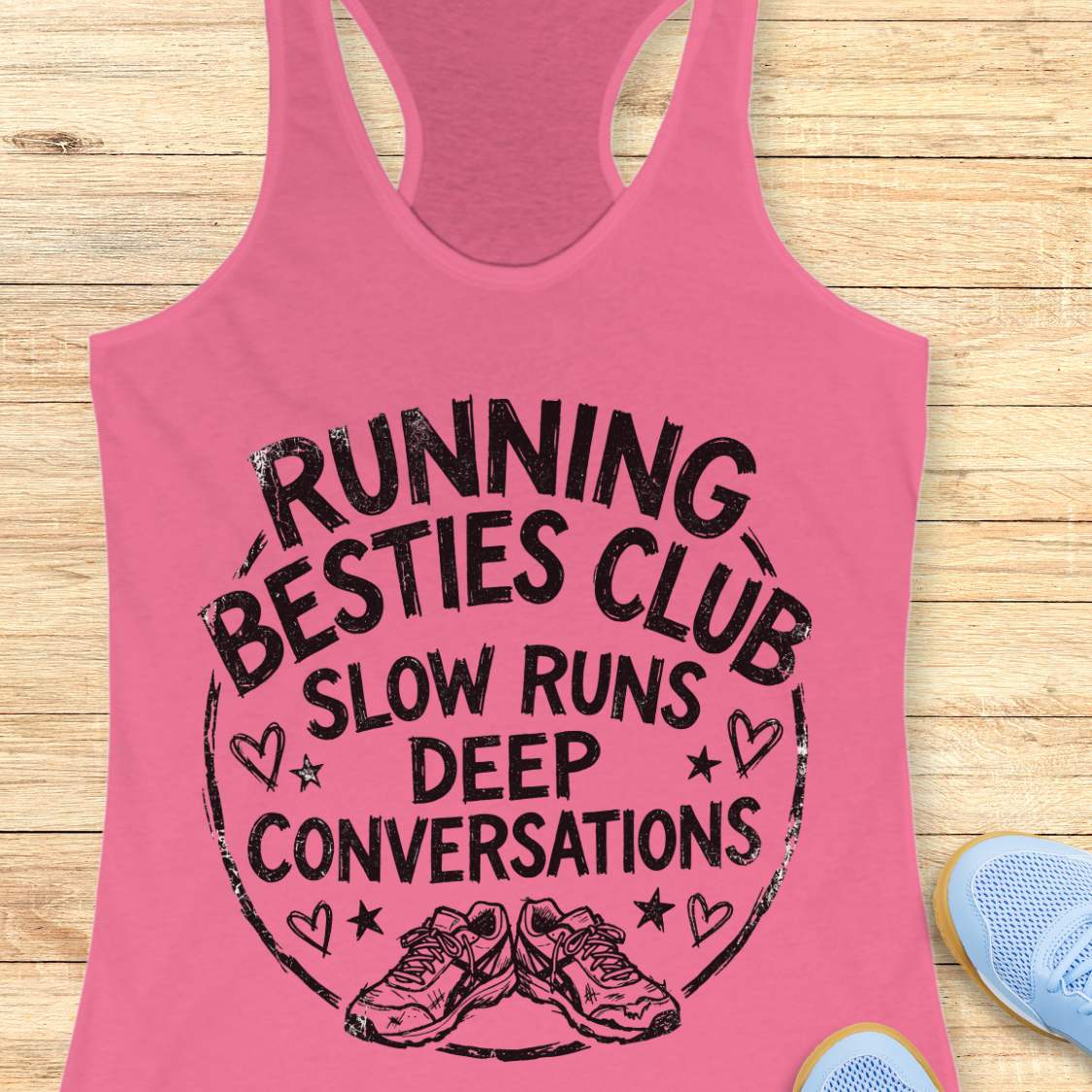 Pink tank top with 'Running Besties Club' text and graphic on a wooden surface.