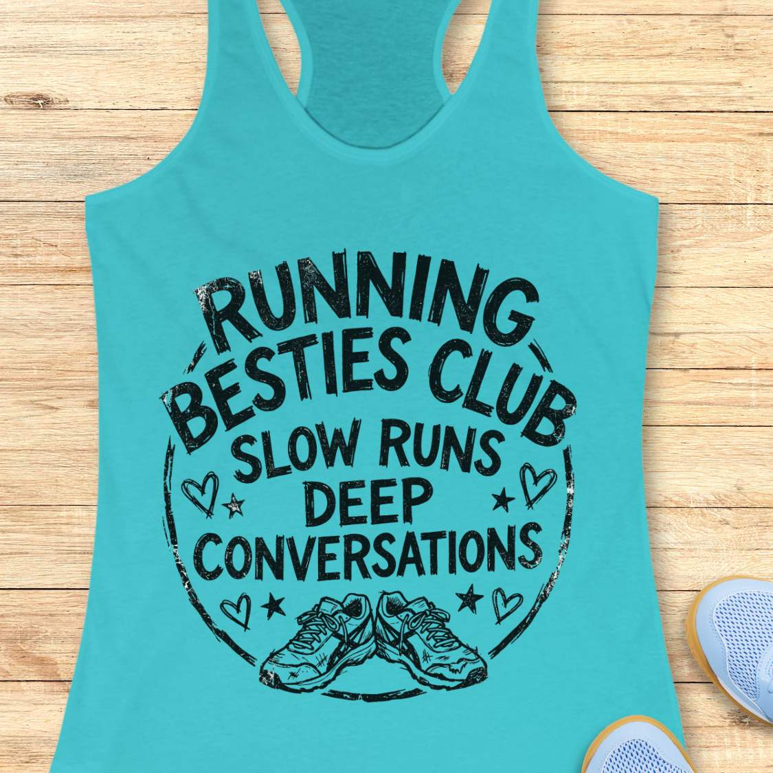 Turquoise tank top with a graphic and text Running besties club, slow runs, deep conversations, on a wooden surface