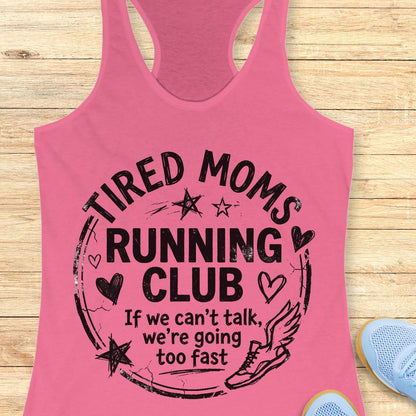 Pink tank top with 'Tired Moms Running Club' text on a wooden surface