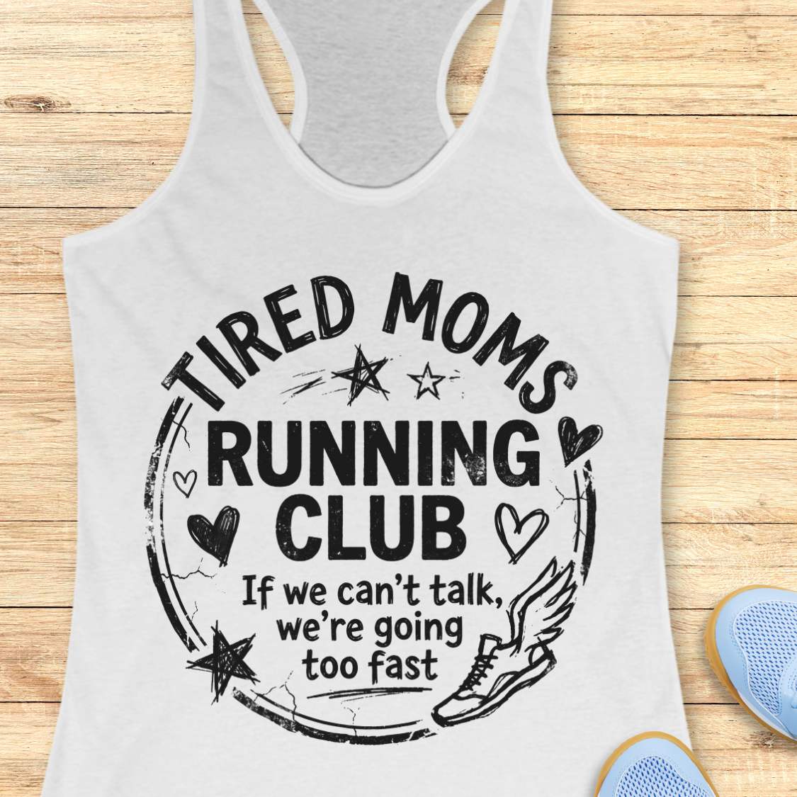 white tank top with 'Tired Moms Running Club' text on a wooden surface