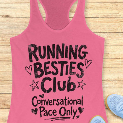 pink tank top with 'Running Besties Club Conversational Pace Only' text on a wooden surface.