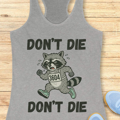 Gray tank top with a raccoon graphic and text 'DON'T DIE' on a wooden surface