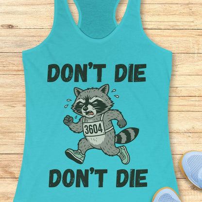 Turquoise tank top with a raccoon graphic and 'Don't Die' text on a wooden surface.