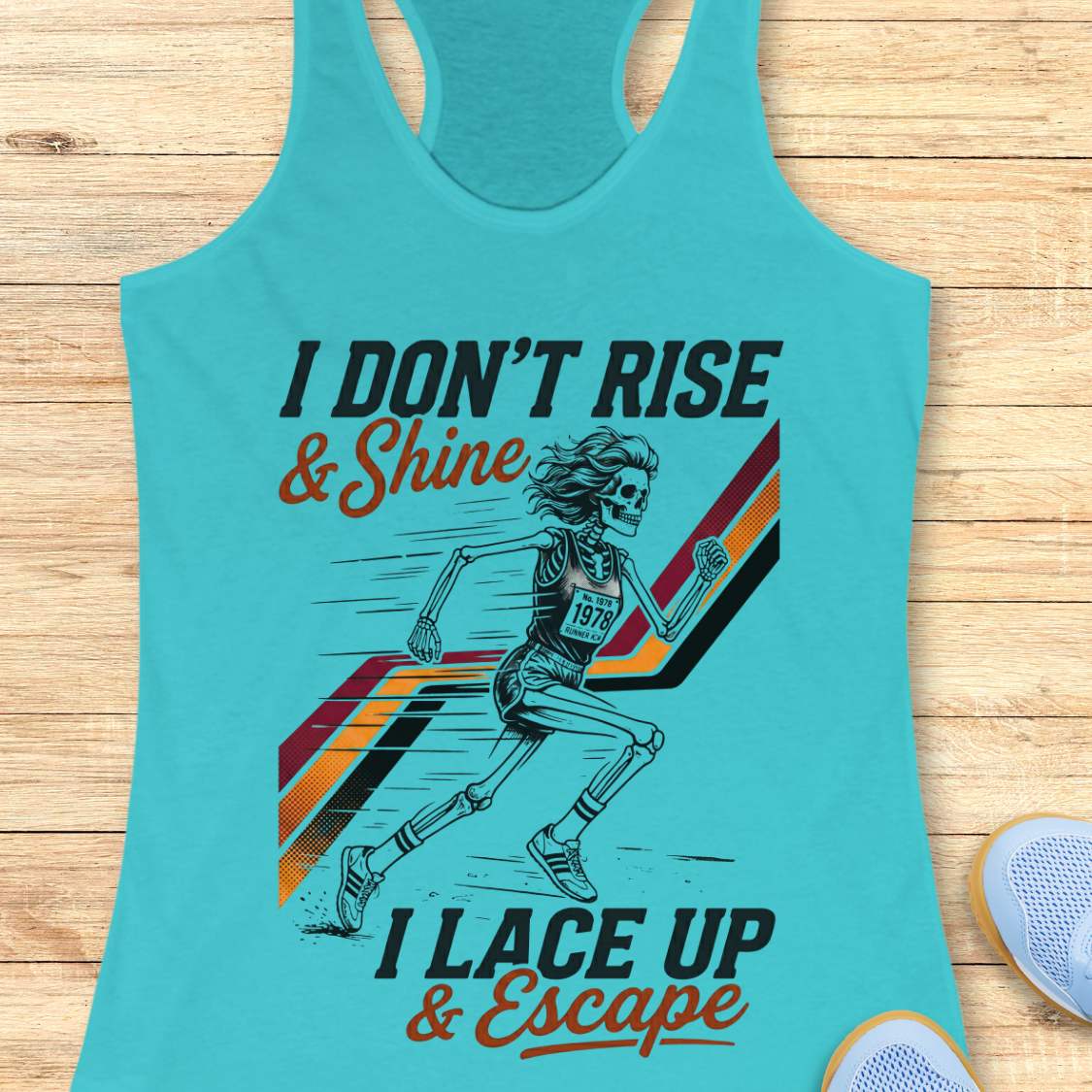 Turquoise tank top with graphic design and text I don't rise & shine, I lace up & escape, on a wooden surface