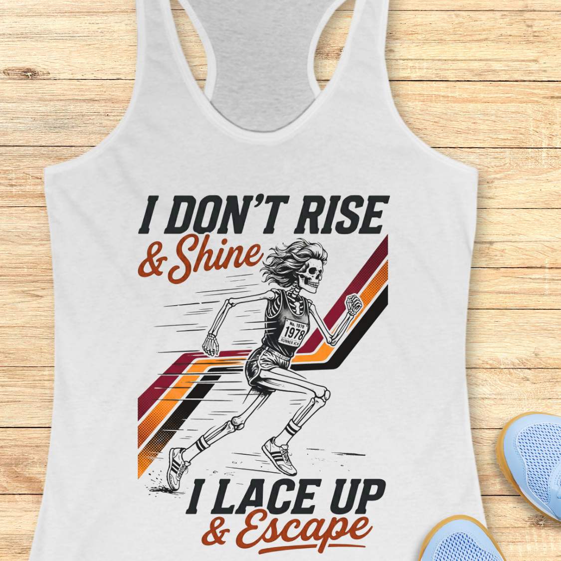 white tank top with running-themed design and text I don't rise & shine, I lace up & escape, on a wooden surface