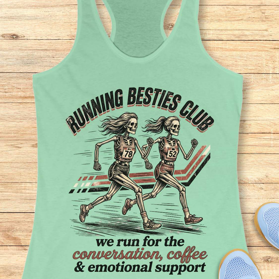 Mint green Tank top with 'Running Besties Club' design featuring skeletons running, on a wooden surface.
