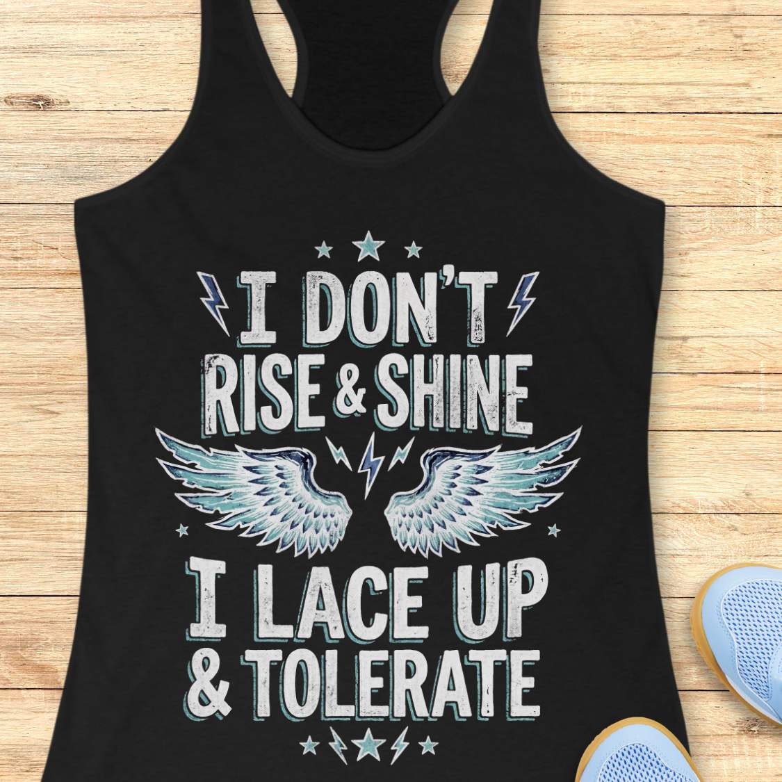 Black tank top with text I don't rise & shine, I lace up & tolerate,  and wings design on a wooden surface