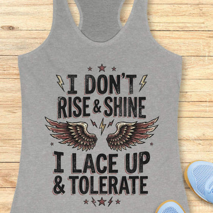 Gray tank top with motivational text I don't rise & shine, I lace up & tolerate,  and wings design on a wooden surface