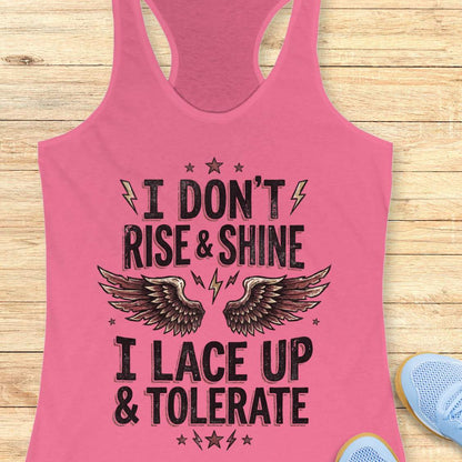 Pink tank top with motivational text I don't rise & shine, I lace up & tolerate,  and wings on a wooden surface