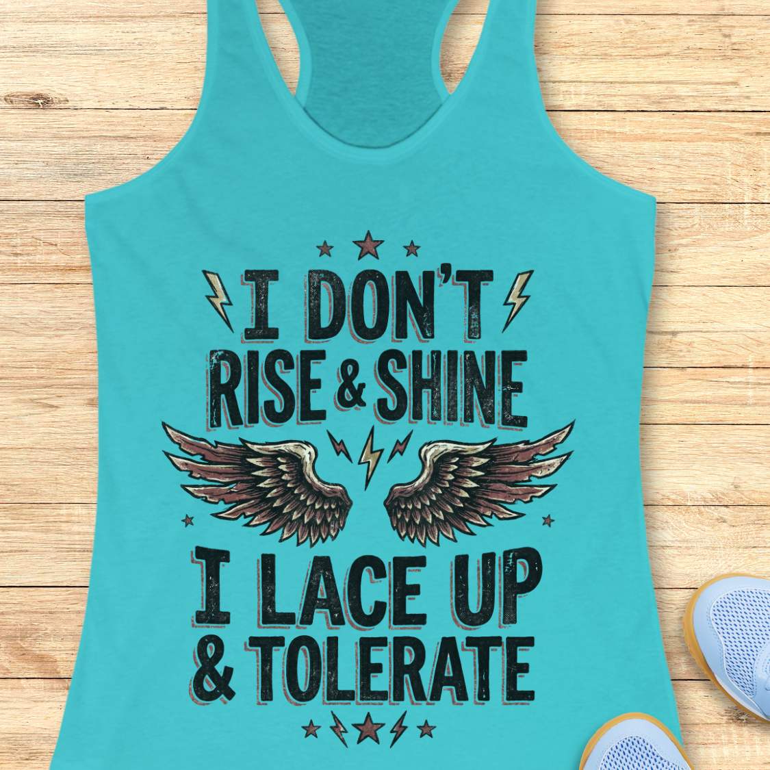 Turquoise tank top with motivational text I don't rise & shine, I lace up & tolerate,  and wings on a wooden surface