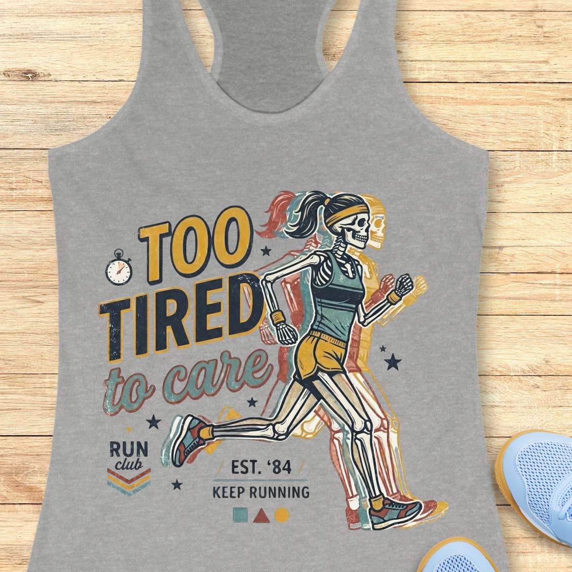 Gray tank top with skeleton runner design and text  too tired to care run club, on a wooden surface