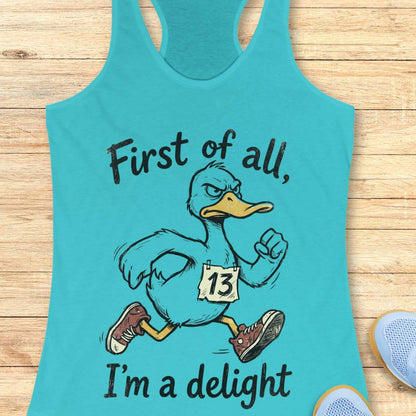 Turquoise tank top with a cartoon duck and text first of all, I'm a delight, on a wooden surface