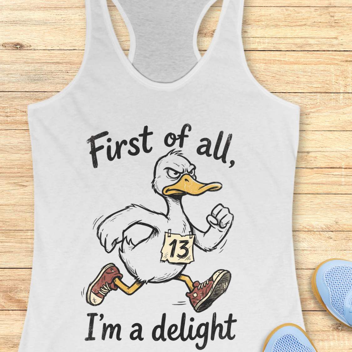white tank top with a cartoon duck and text first of all, I'm a delight, on a wooden surface