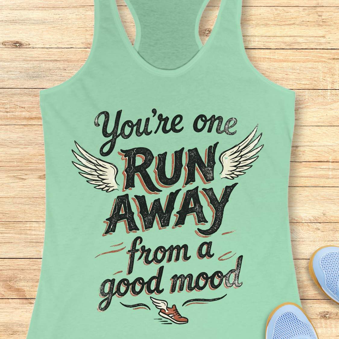 Mint green tank top with text 'You're one run away from a good mood' on a wooden surface.