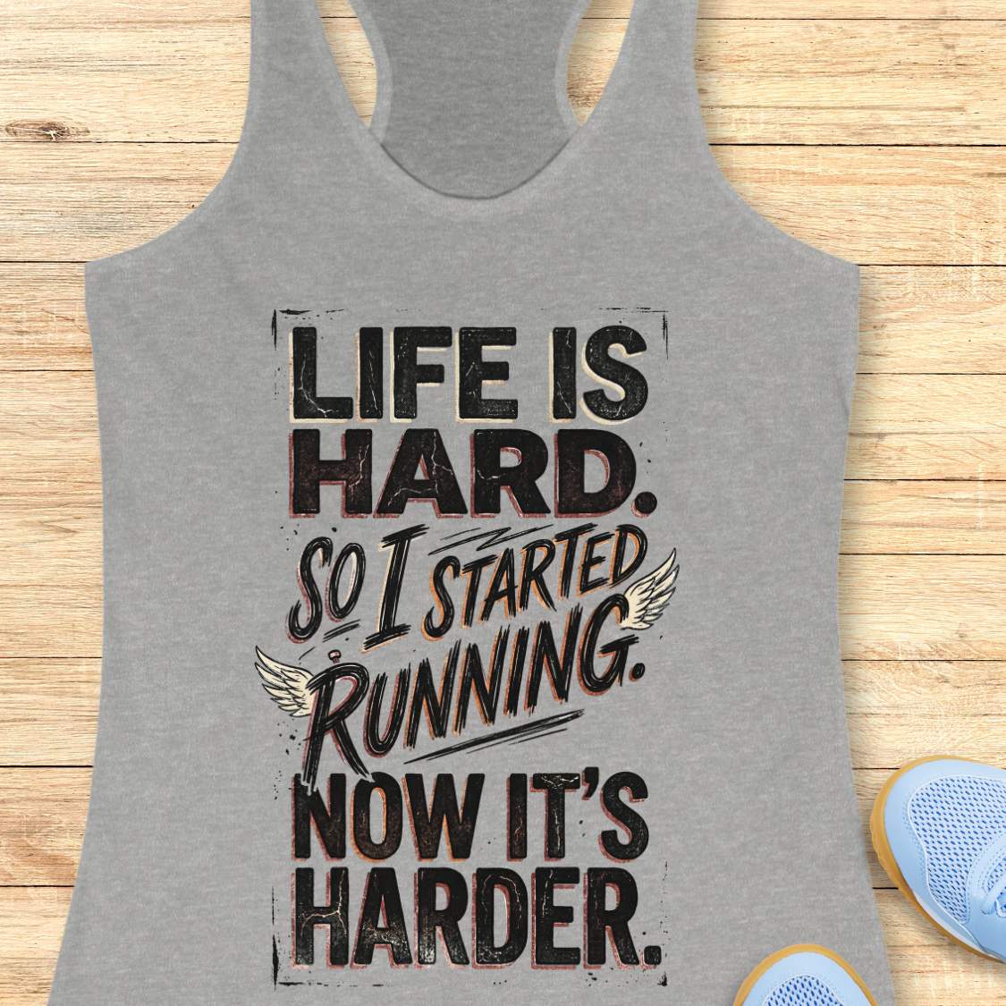 Gray tank top with with funny quote life is hard. So I started running. Now it's harder. on a wooden surface