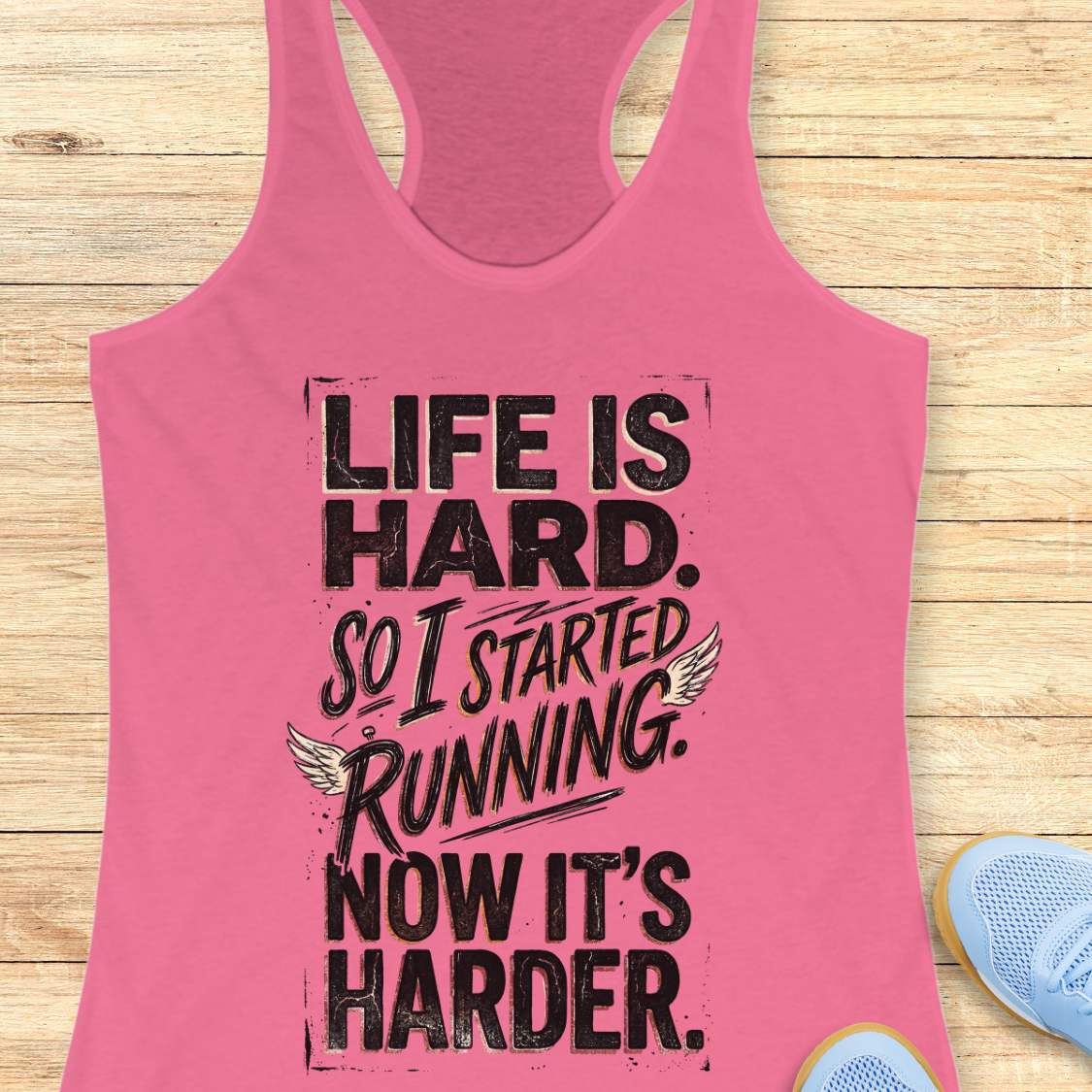 Pink tank top with with funny quote life is hard. So I started running. Now it's harder. on a wooden surface