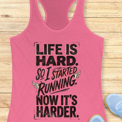 Pink tank top with with funny quote life is hard. So I started running. Now it's harder. on a wooden surface