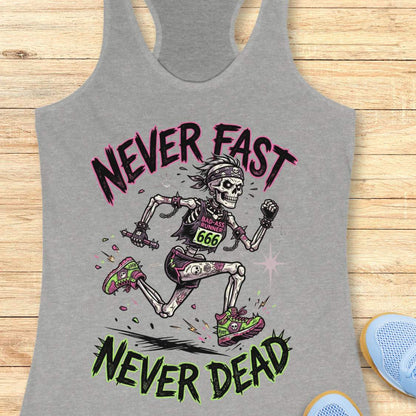Gray tank top with skeleton running design and text 'Never Fast Never Dead' on a wooden surface.