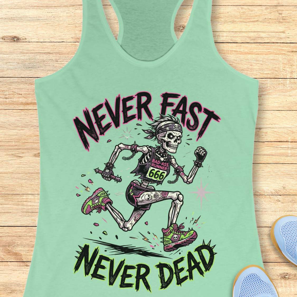 Mint green tank top with skeleton graphic and text 'Never Fast, Never Dead' on a wooden surface.