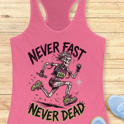 Pink tank top with skeleton graphic and text 'Never Fast Never Dead' on a wooden surface.
