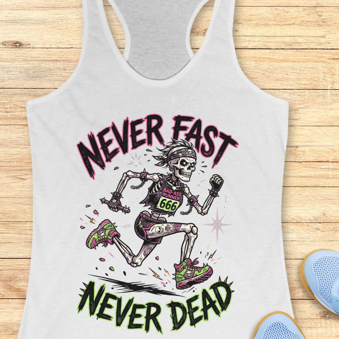 White tank top with skeleton runner graphic and text 'Never Fast Never Dead' on a wooden surface.