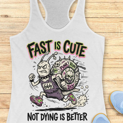 White tank top with cartoon character and text 'Fast is cute, not dying is better' on a wooden surface.