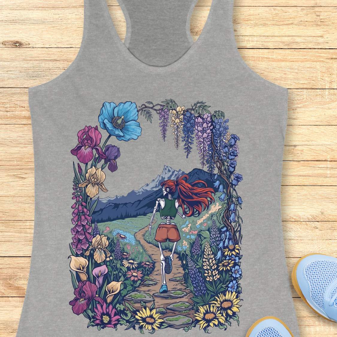Gray tank top with a colorful graphic of a person with red hair walking through flowers on a wooden surface.