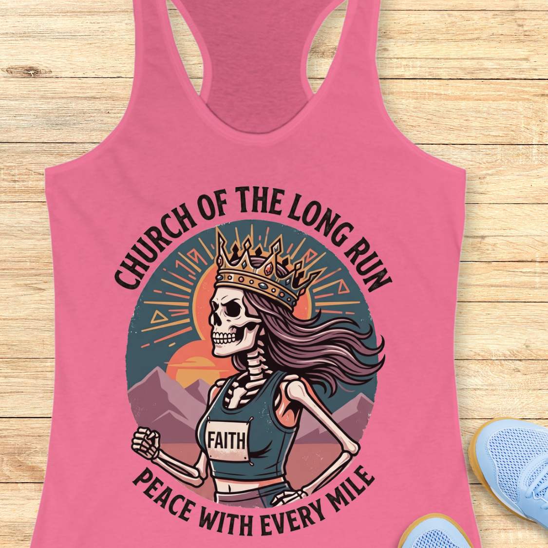 Pink tank top with skeleton design and text Church of the long run, peace with every mile, on a wooden surface