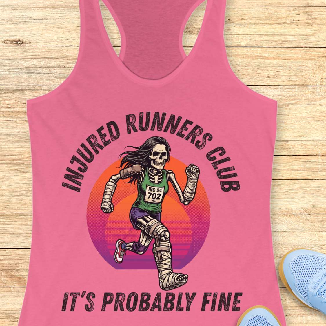 Pink tank top with 'Injured Runners Club' graphic on a wooden surface