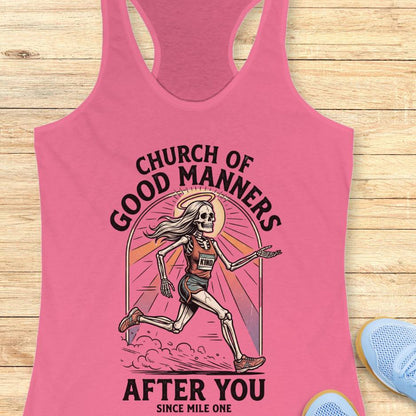 Pink tank top with skeleton graphic and text 'Church of Good Manners After You Since Mile One' on a wooden surface.