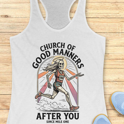 White tank top with skeleton design and text 'Church of Good Manners After You Since Mile One' on a wooden surface.