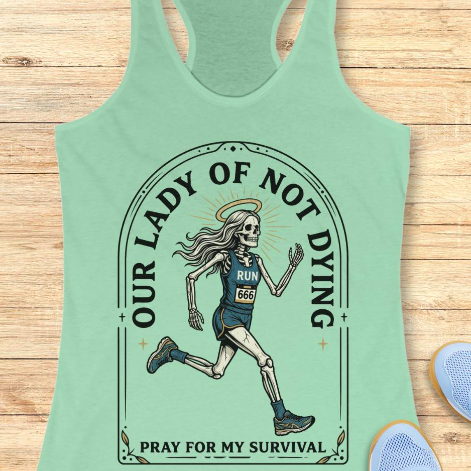 Mint green tank top with skeleton runner design and text Our lady of noy dying, pray for my survival,  on a wooden surface