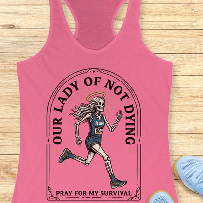 Pink tank top with skeleton runner graphic and text Our lady of noy dying, pray for my survival,  on a wooden surface