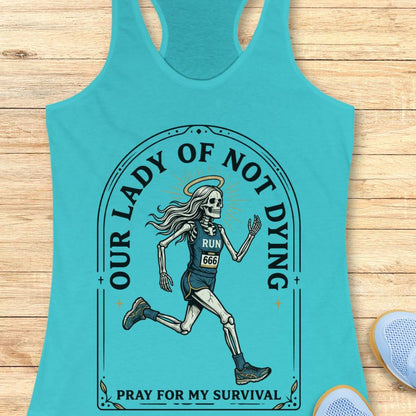 Turquoise tank top with skeleton graphic and text Our lady of noy dying, pray for my survival, on a wooden surface