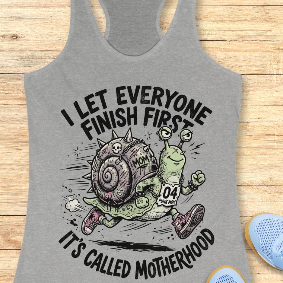 Gray tank top with a graphic of a snail and text  I let everyone finish first, It's called motherhood, on a wooden surface