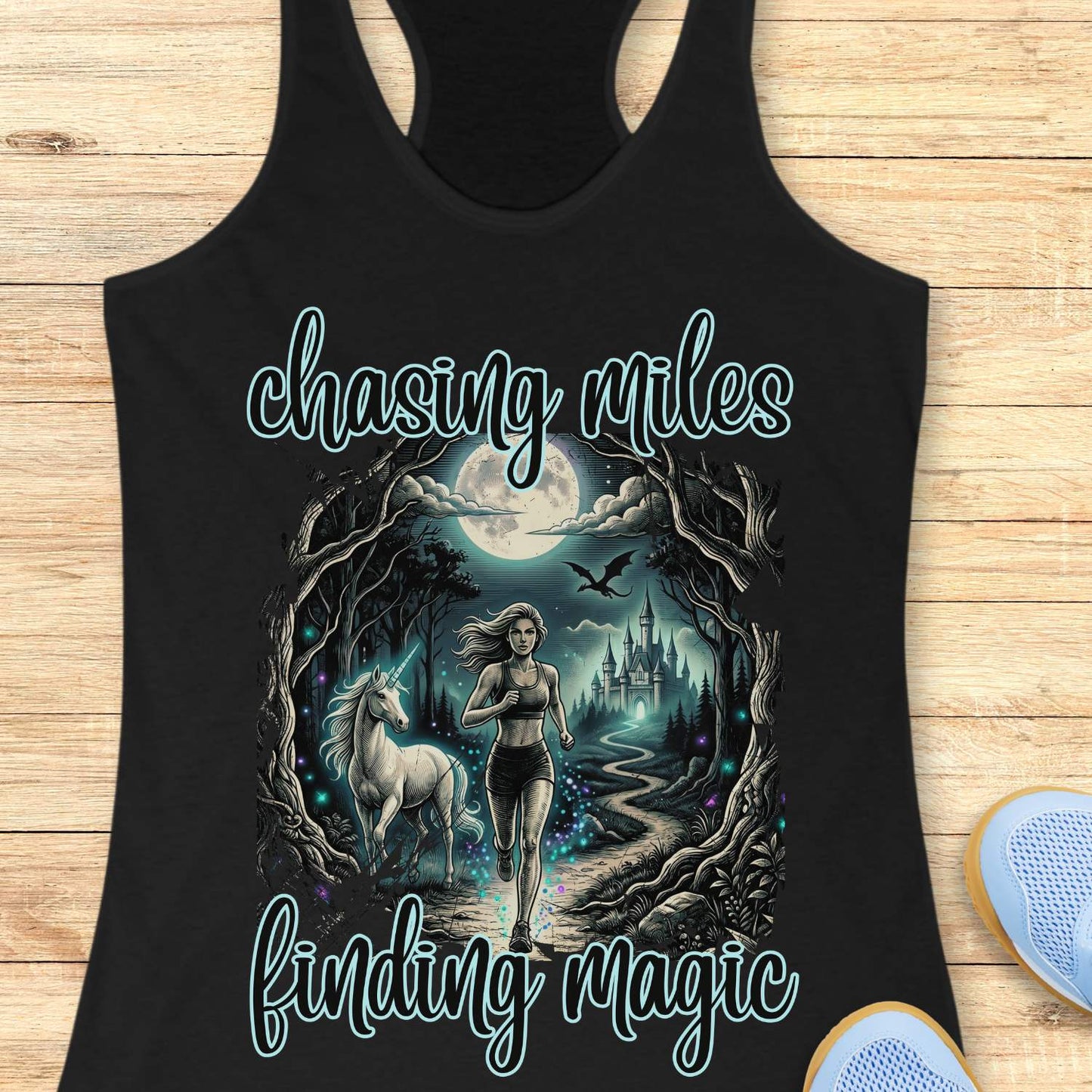 Black tank top with a graphic of a woman running with a unicorn and text 'chasing miles finding magic' on a wooden surface.