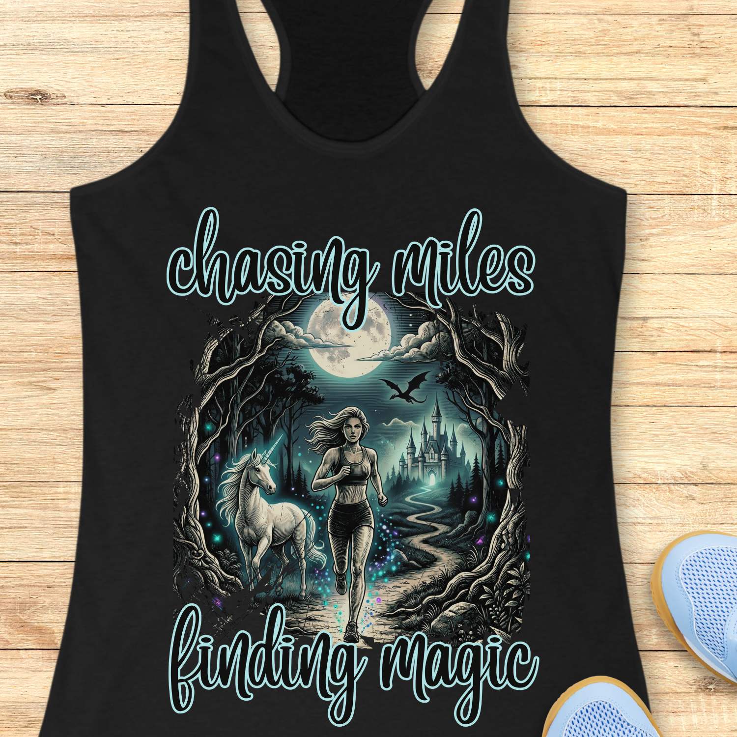 Black tank top with a graphic of a woman running with a unicorn and text 'chasing miles finding magic' on a wooden surface.