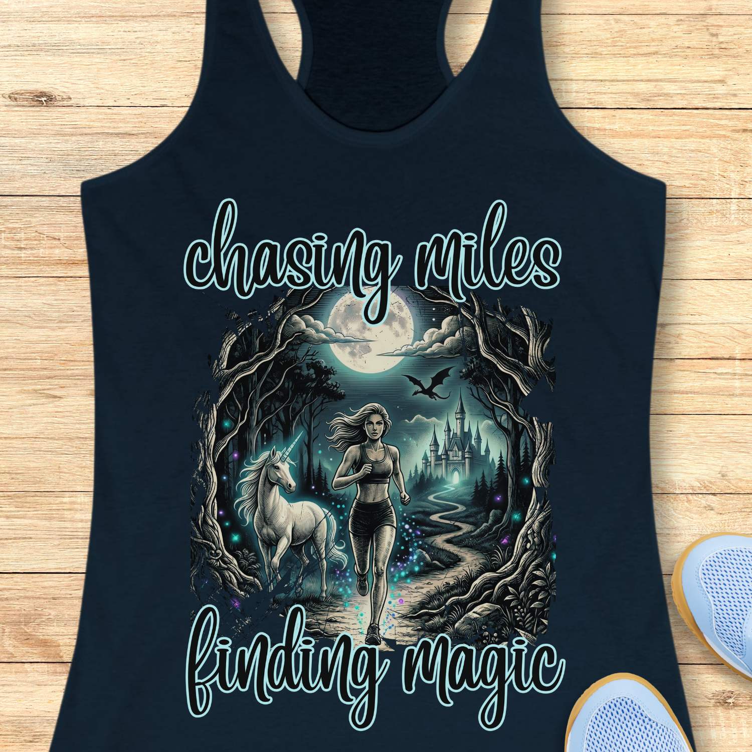 Navy tank top with a graphic of a woman running with a unicorn and text 'chasing miles finding magic' on a wooden surface.