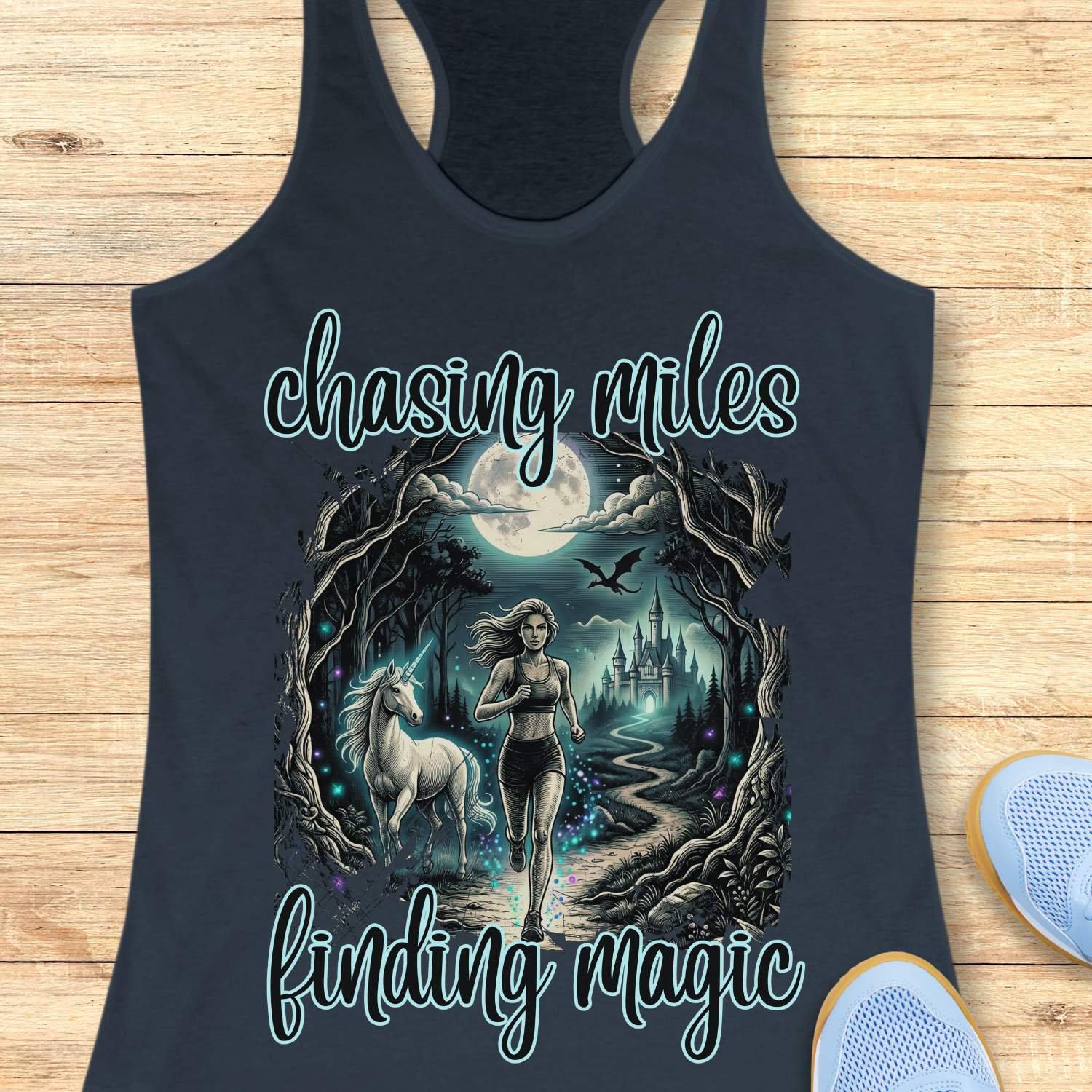 Indigo tank top with a graphic of a woman running with a unicorn and text 'chasing miles finding magic' on a wooden surface.