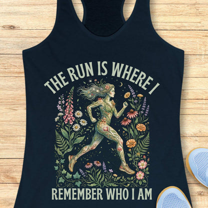 navy tank top with a graphic design of a woman running surrounded by flowers and text The run is where I remember who I am ,on a wooden surface.
