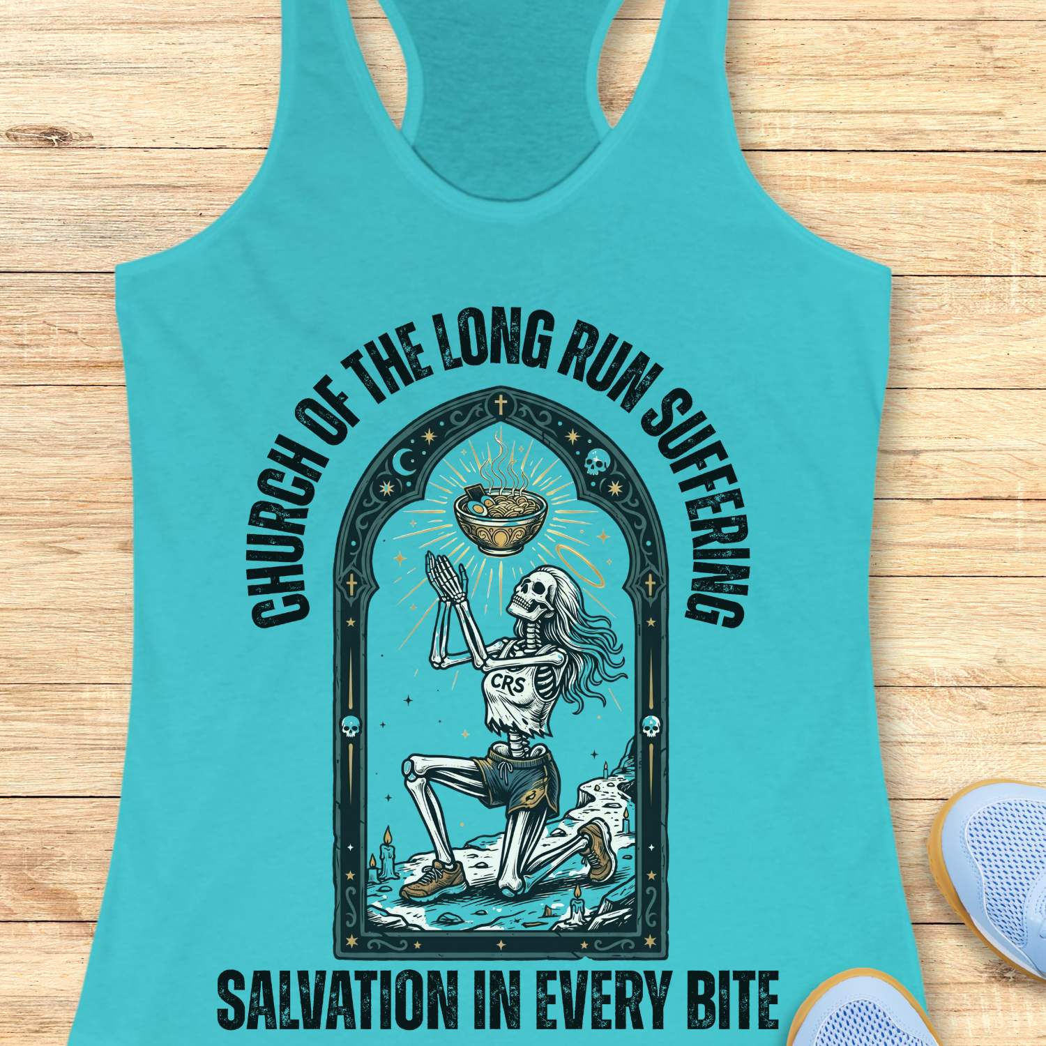 Turquoise tank top with skeleton design and text 'Church of the long run suffering. Salvation in every bite', on a wooden surface
