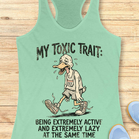 Mint green tank top with cartoon character and text ' my toxic trait - being extremely active and extremely lazy at the same time', on a wooden surface